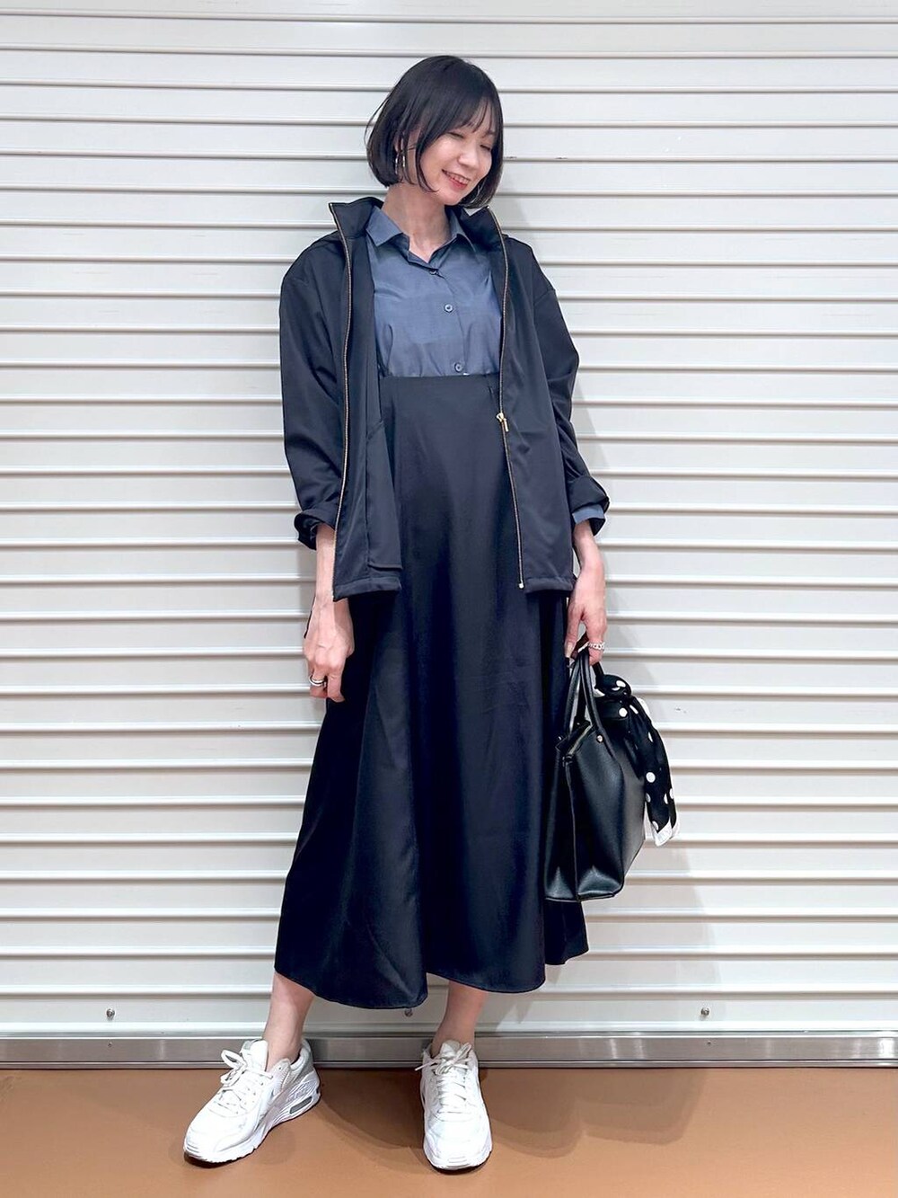 ブルー系のスカート、ブラック系のショルダーバッグ、ブルー系のシャツ/ブラウスを着用したレディースの春コーディネートの2枚目の写真