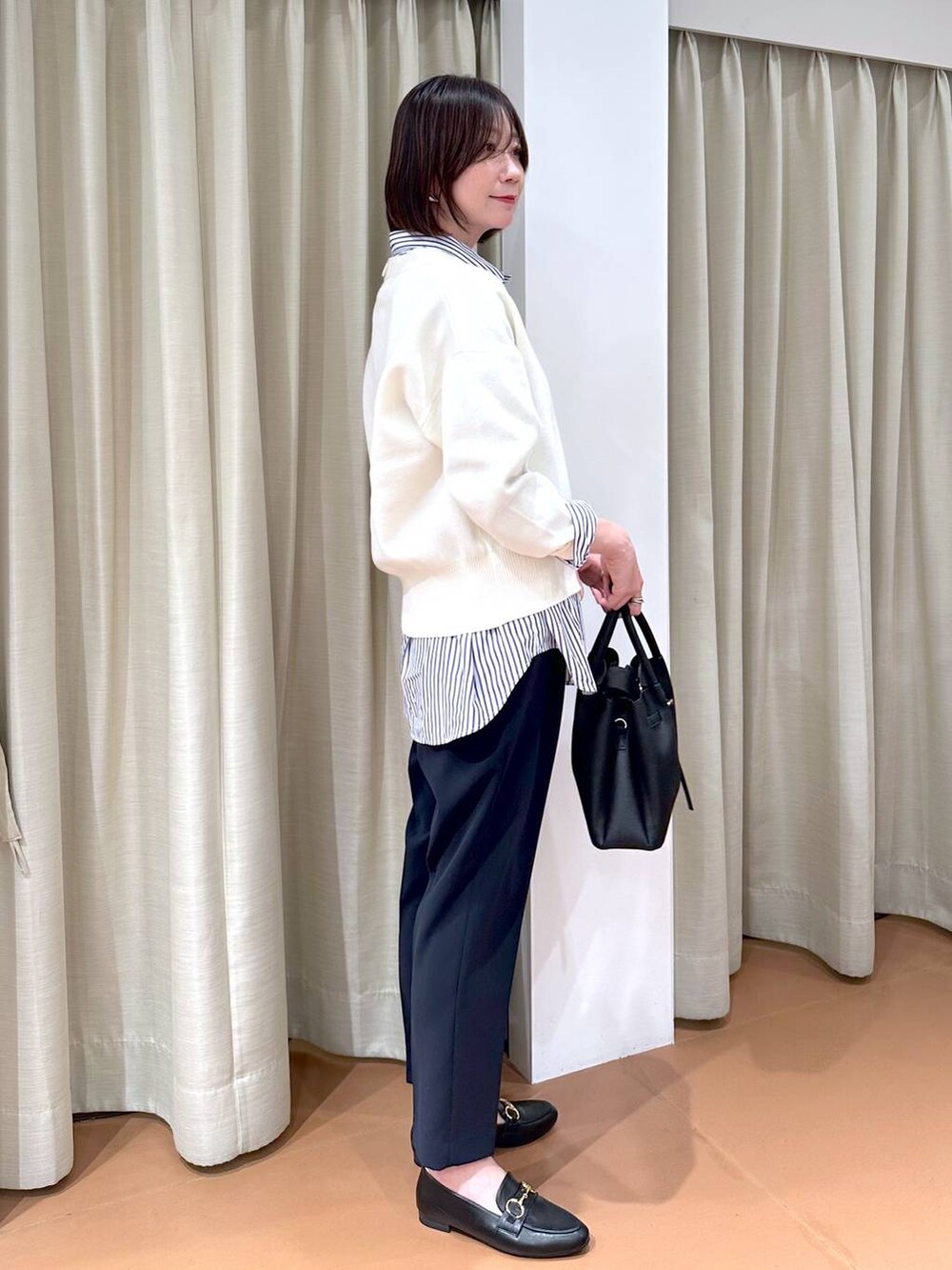 ブラック系のローファー、ブルー系のスーツパンツ、ブラック系のハンドバッグを着用したレディースの冬コーディネートの4枚目の写真