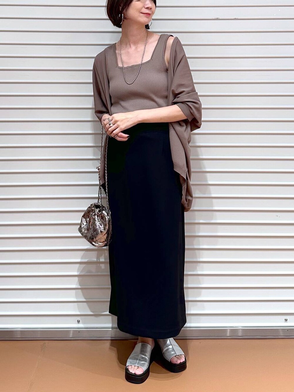 ブラック系のスカート、ブラウン系のカーディガン/ボレロ、シルバー系のサンダルを着用したレディースの夏コーディネートの5枚目の写真