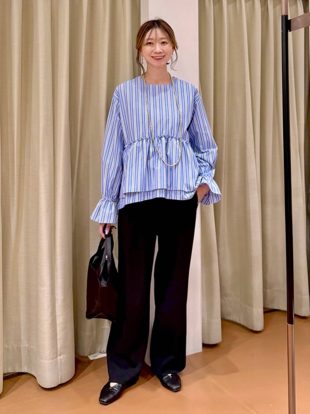 ブラック系のその他パンツ、ブラック系のパンプス、ブルー系のシャツ/ブラウスを着用したレディースの春コーディネートの2枚目の写真