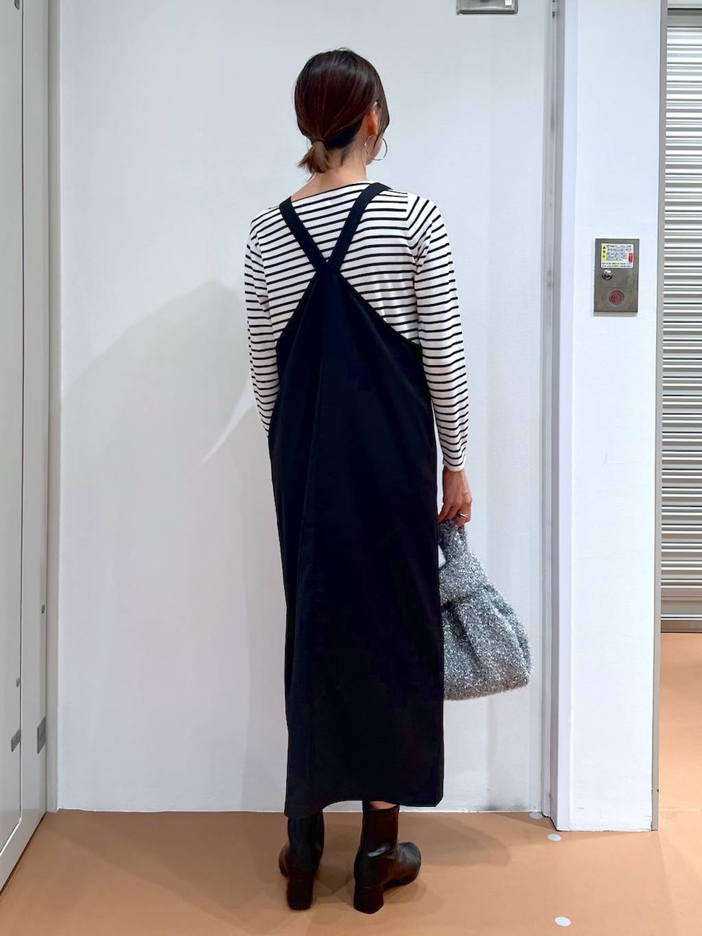 ブラック系のニット/セーター、ブラック系のブーツ、シルバー系のハンドバッグを着用したレディースの秋コーディネートの4枚目の写真