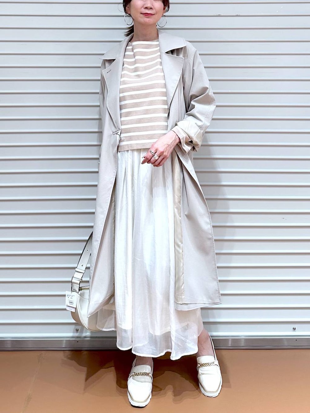 ホワイト系のスカート、ホワイト系のローファー、ホワイト系のハンドバッグを着用したレディースの冬コーディネートの4枚目の写真