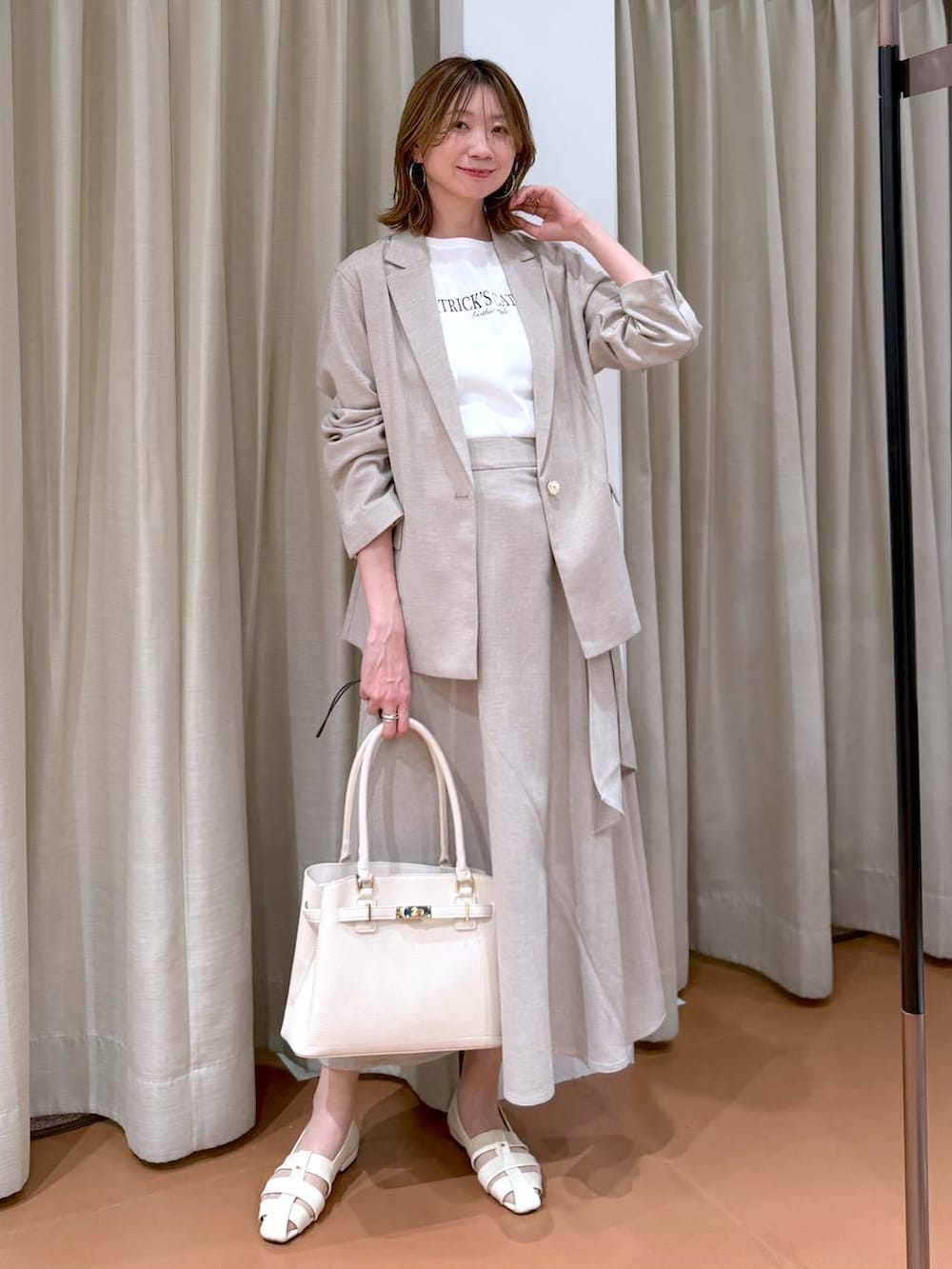 ホワイト系のハンドバッグ、ホワイト系のパンプス、ホワイト系のTシャツ/カットソーを着用したレディースの春コーディネートの2枚目の写真