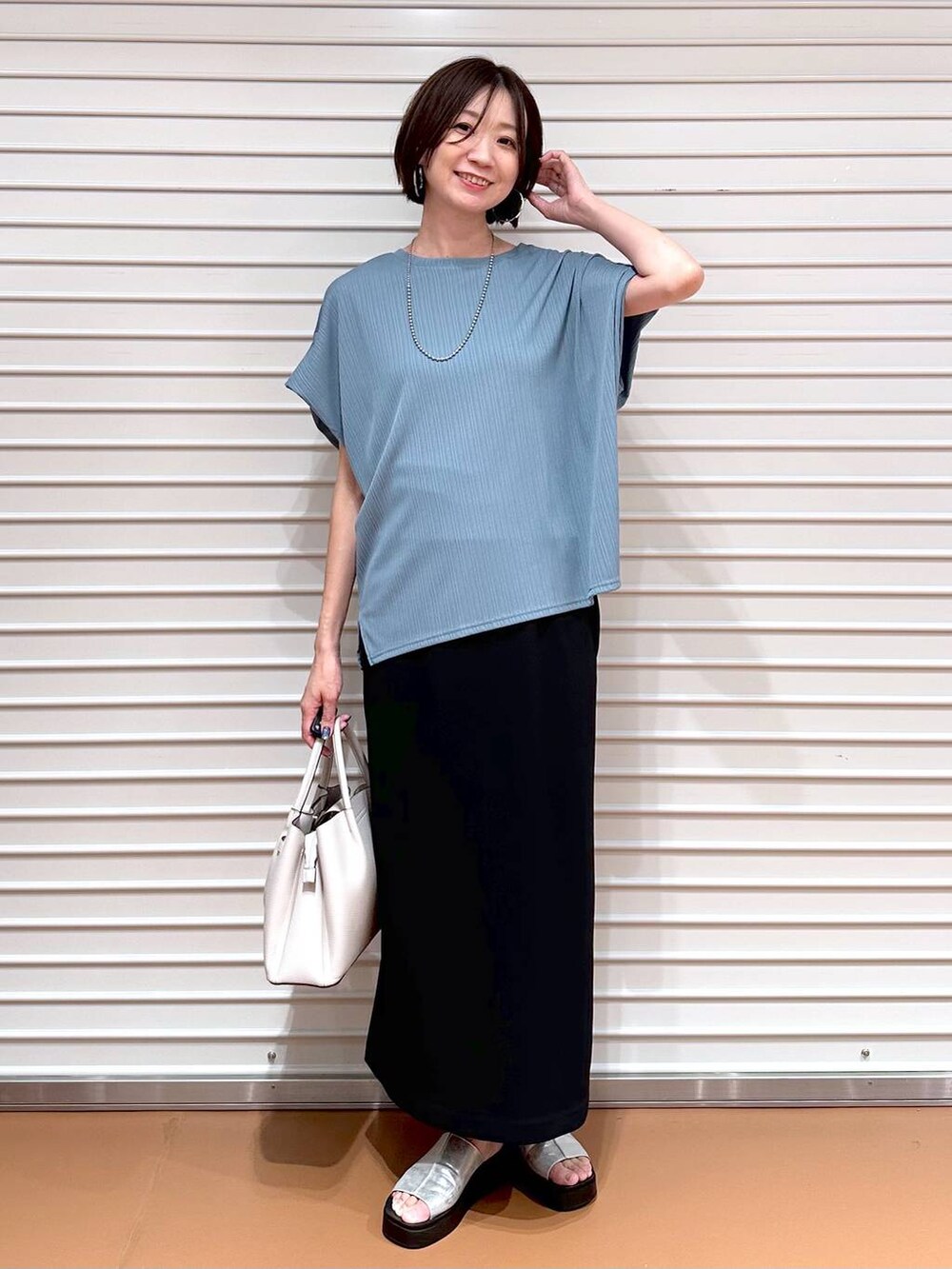 グリーン系のTシャツ/カットソー、シルバー系のサンダル、ブラック系のスカートを着用したレディースの秋コーディネートの2枚目の写真