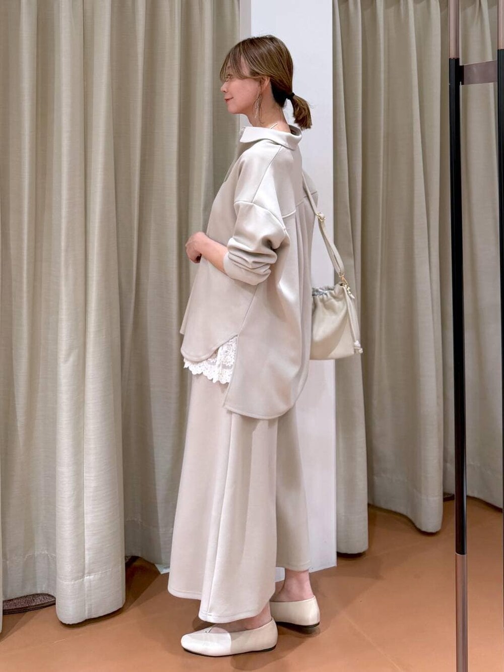 ホワイト系のハンドバッグ、ホワイト系のパンプス、ホワイト系のタンクトップを着用したレディースの冬コーディネートの3枚目の写真