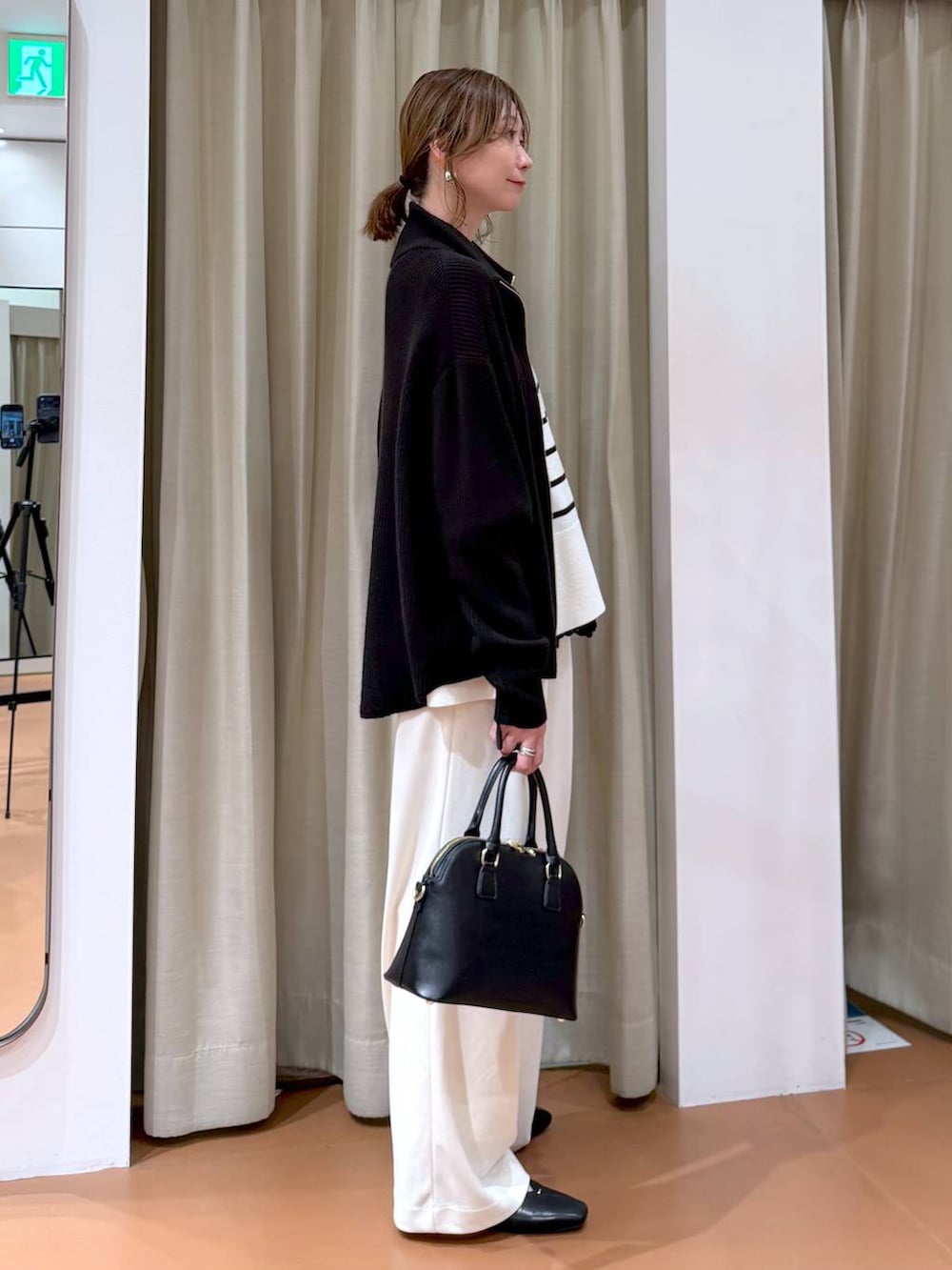 ホワイト系のニット/セーター、ブラック系のカーディガン/ボレロ、ブラック系のハンドバッグを着用したレディースの冬コーディネートの3枚目の写真