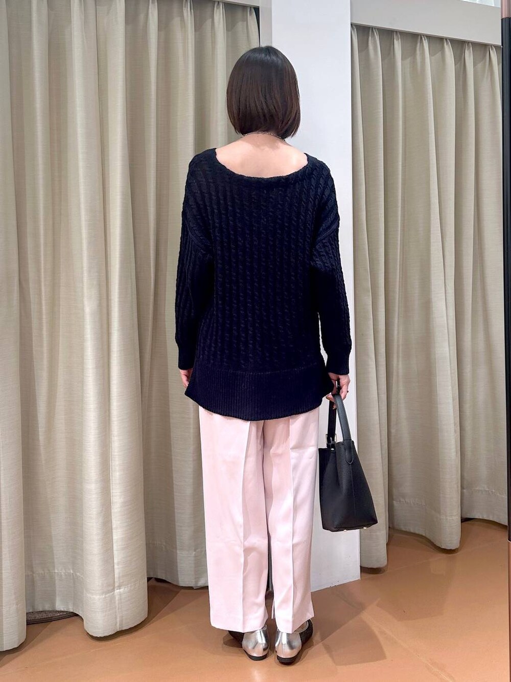 ブルー系のニット/セーター、ブラック系のハンドバッグ、シルバー系のパンプスを着用したレディースの冬コーディネートの4枚目の写真