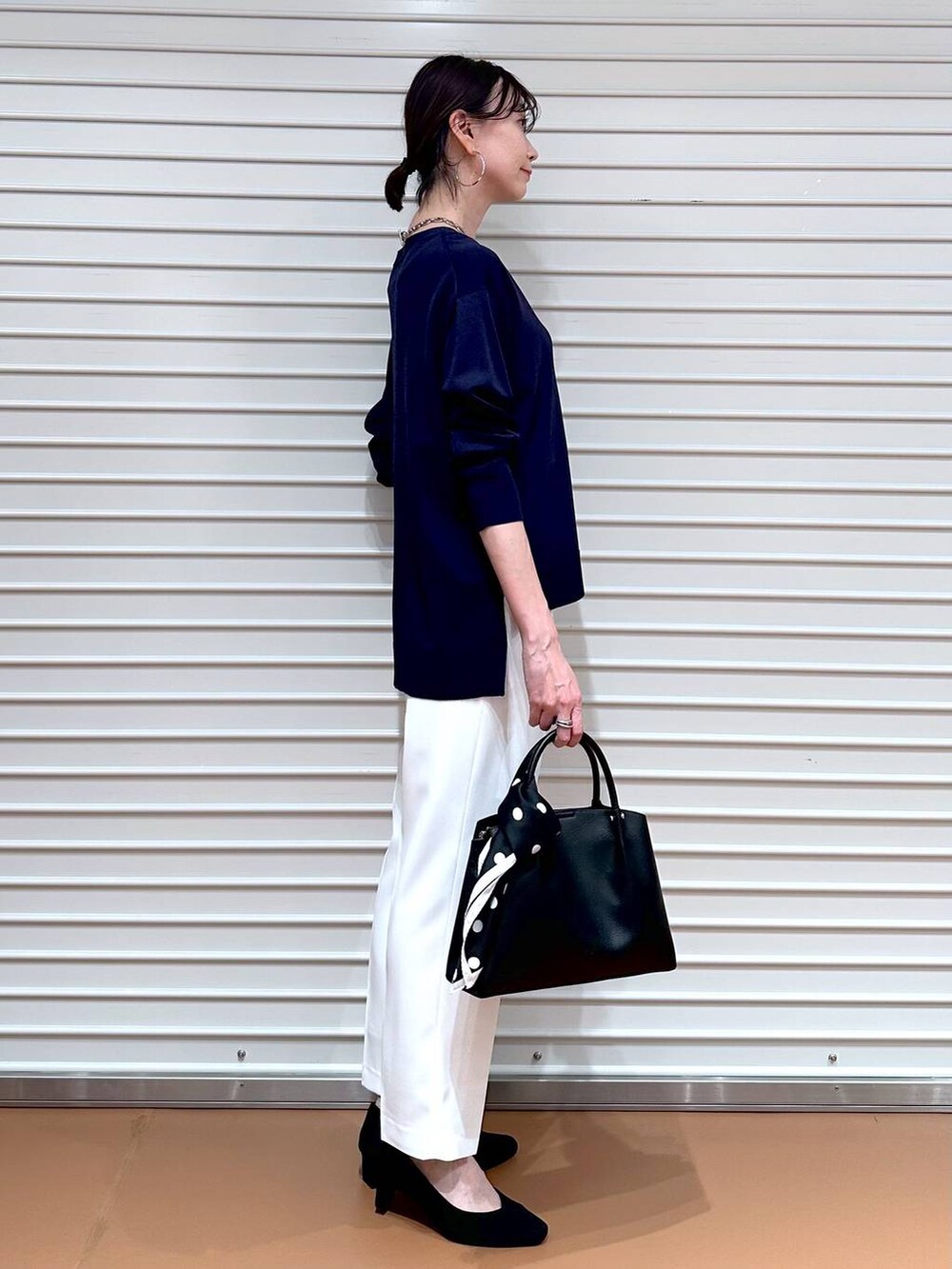 ブルー系のニット/セーター、ブラック系のショルダーバッグ、ホワイト系のその他パンツを着用したレディースの春コーディネートの5枚目の写真