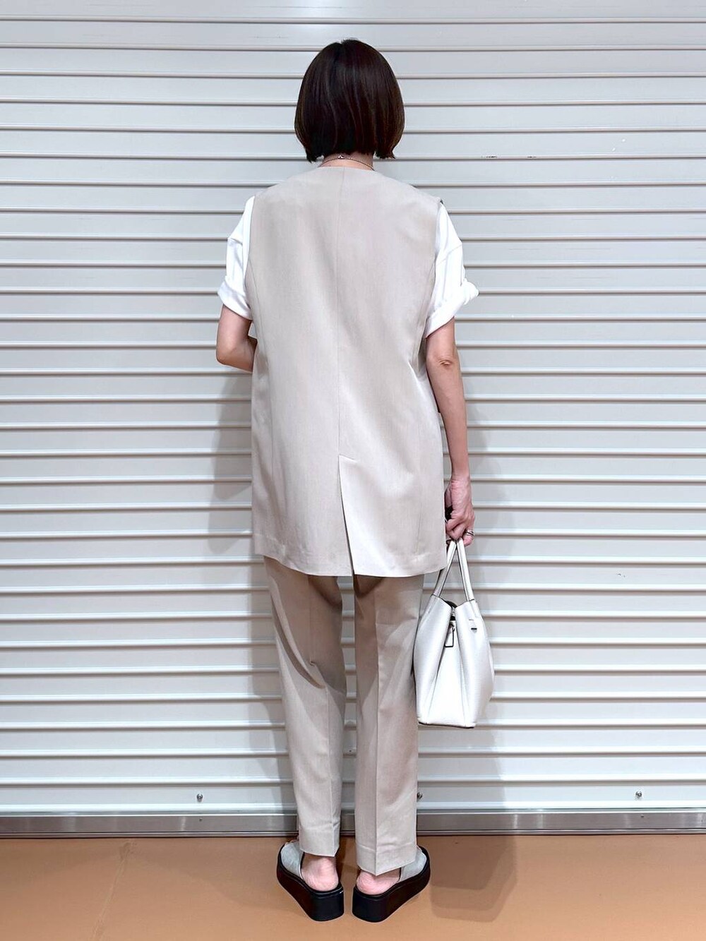 ベージュ系のベスト、シルバー系のサンダル、ホワイト系のTシャツ/カットソーを着用したレディースの夏コーディネートの4枚目の写真