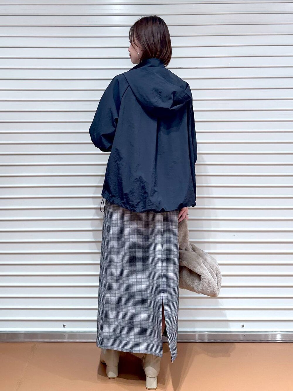 ブラック系のスカート、ブラウン系のTシャツ/カットソー、ブルー系のマウンテンパーカーを着用したレディースの秋コーディネートの5枚目の写真