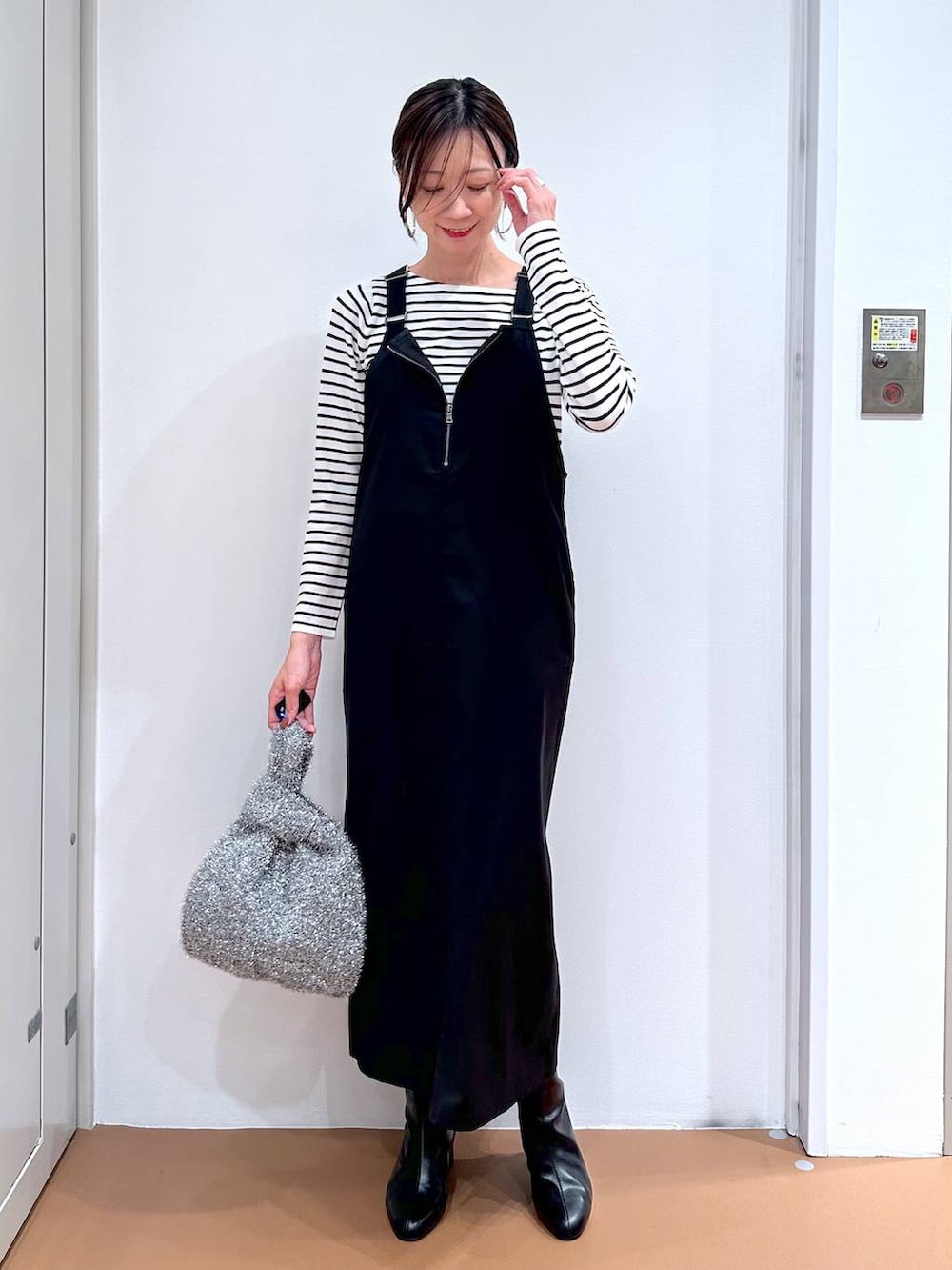 ブラック系のニット/セーター、ブラック系のブーツ、シルバー系のハンドバッグを着用したレディースの秋コーディネートの2枚目の写真