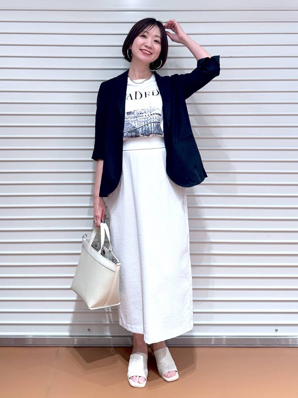 ホワイト系のサンダル、ホワイト系のトートバッグ、グレー系のスカートを着用したレディースの秋コーディネートの2枚目の写真