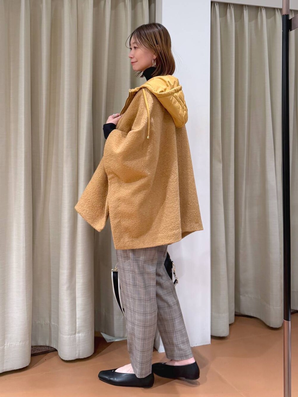 ブラック系のハンドバッグ、ブラック系のスラックス、ブラック系のパンプスを着用したレディースの冬コーディネートの3枚目の写真