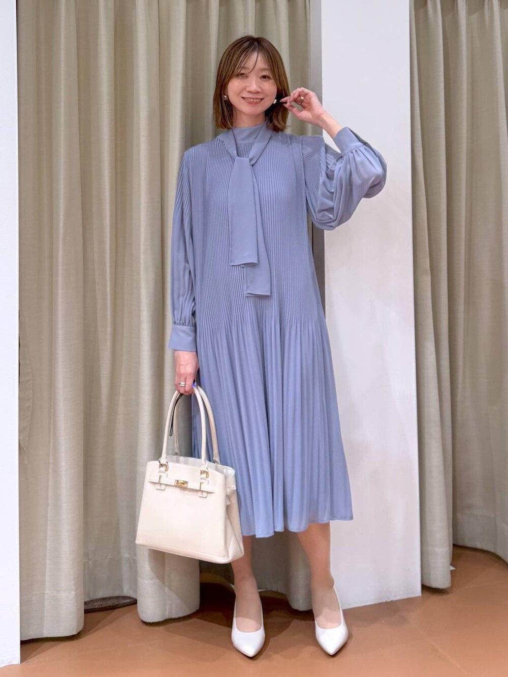 ベージュ系のパンプス、ブルー系のワンピース、ホワイト系のハンドバッグを着用したレディースの冬コーディネートの2枚目の写真