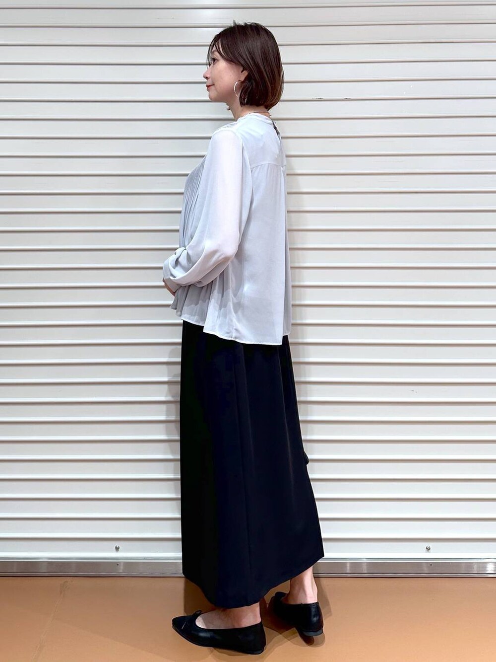 ブラック系のスカート、ブラック系のパンプス、ブラック系のハンドバッグを着用したレディースの秋コーディネートの3枚目の写真