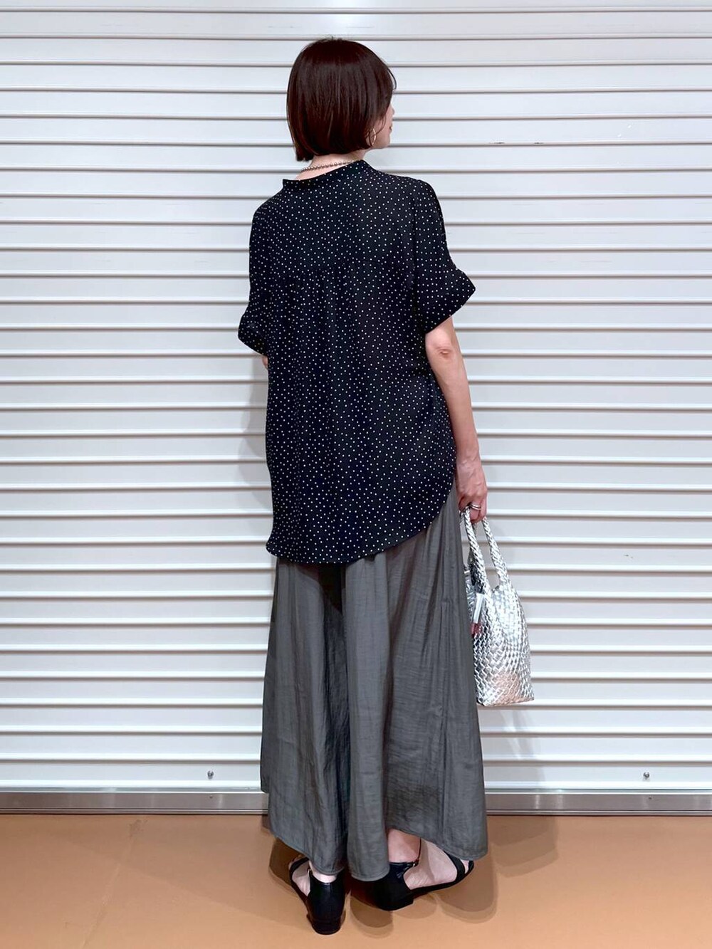 シルバー系のトートバッグ、ブラック系のサンダル、ブラック系のシャツ/ブラウスを着用したレディースの夏コーディネートの4枚目の写真