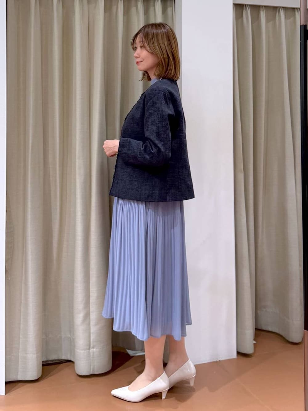 ベージュ系のパンプス、ブルー系のノーカラージャケット、ブルー系のワンピースを着用したレディースの冬コーディネートの3枚目の写真