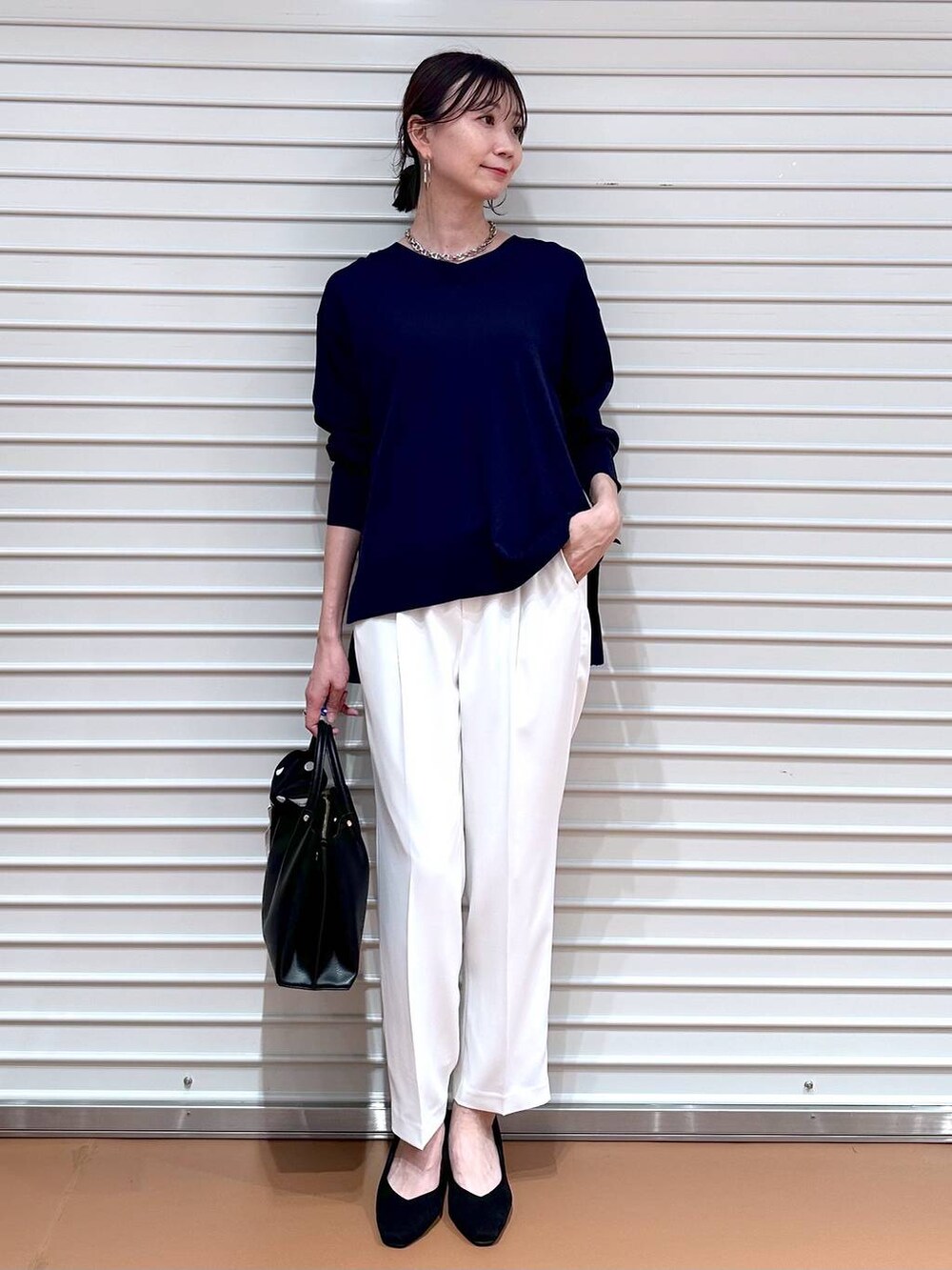 ブルー系のニット/セーター、ブラック系のショルダーバッグ、ホワイト系のその他パンツを着用したレディースの春コーディネートの2枚目の写真