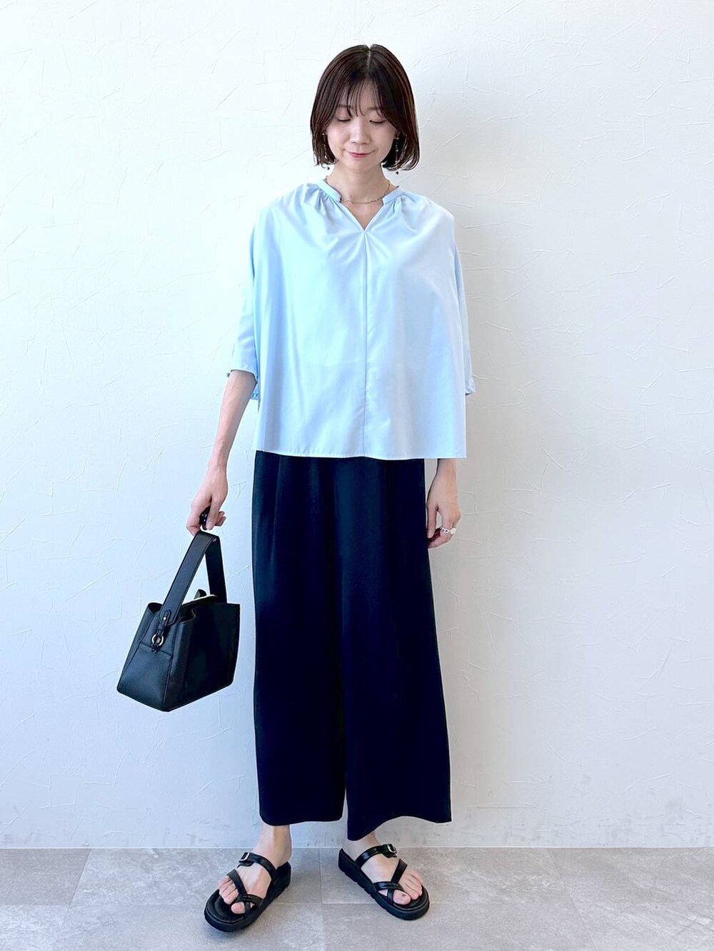 ブラック系のサンダル、ブルー系のシャツ/ブラウス、ブラック系のハンドバッグを着用したレディースの夏コーディネートの2枚目の写真