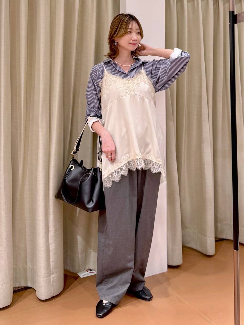 ブラック系のパンプス、ホワイト系のキャミソール、ブラック系のトートバッグを着用したレディースの春コーディネートの2枚目の写真