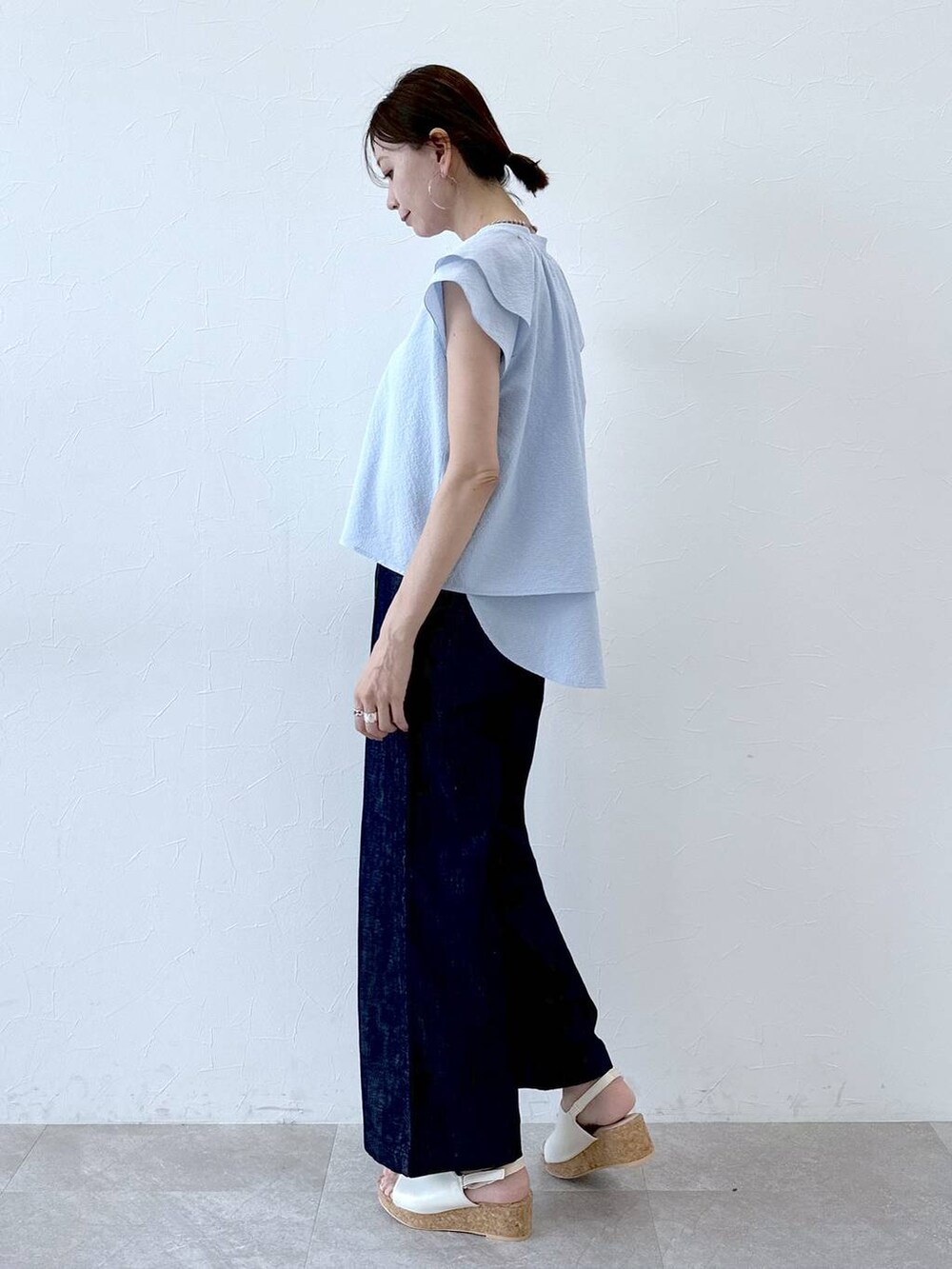 ブルー系のデニムパンツ、ブルー系のデニムパンツ、ホワイト系のサンダルを着用したレディースの夏コーディネートの3枚目の写真