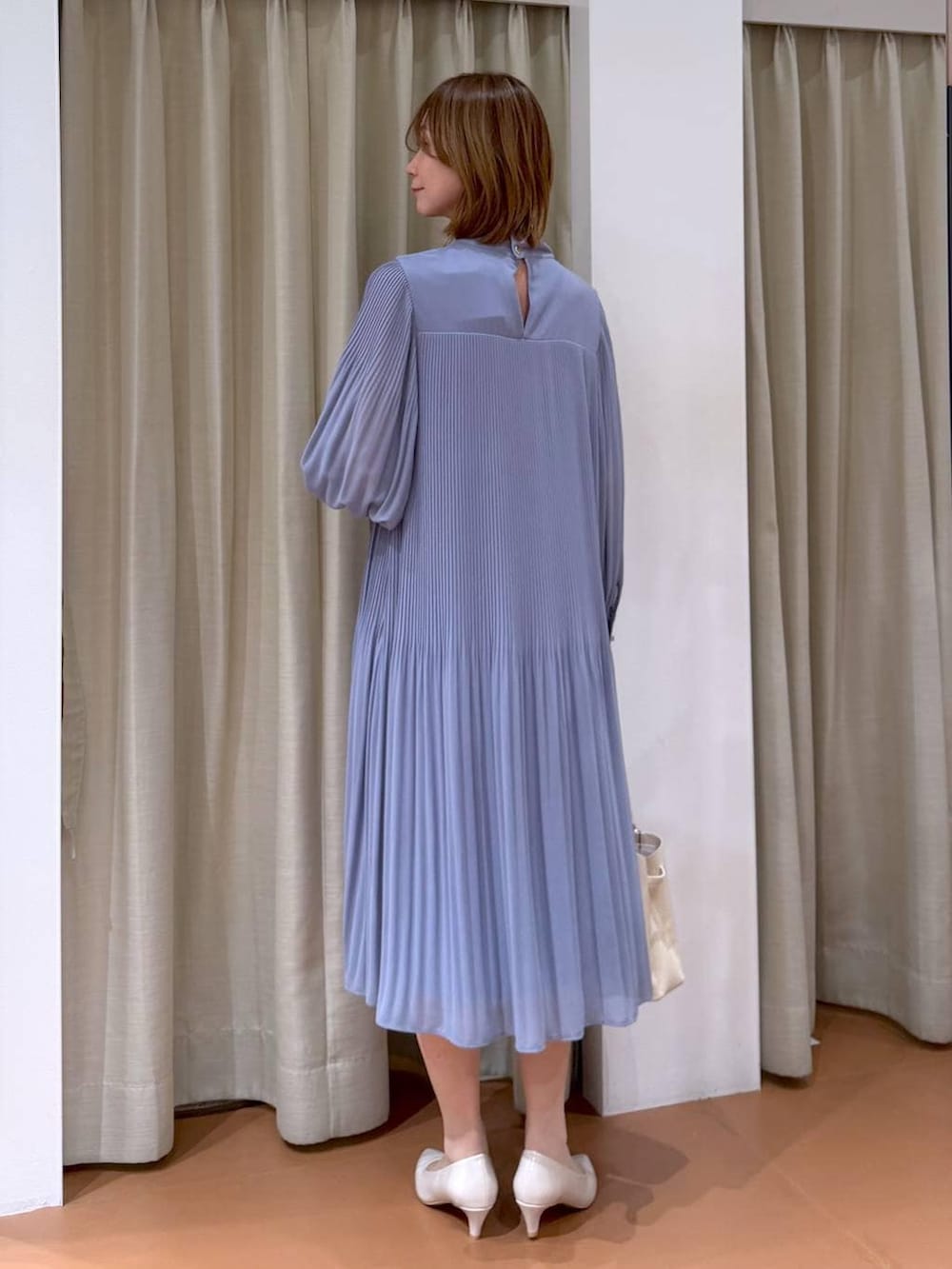 ベージュ系のパンプス、ブルー系のワンピース、ホワイト系のハンドバッグを着用したレディースの冬コーディネートの4枚目の写真