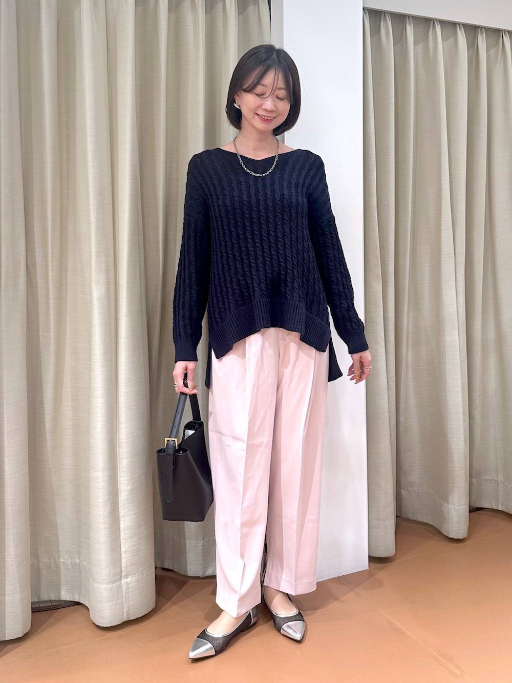 ブルー系のニット/セーター、ブラック系のハンドバッグ、シルバー系のパンプスを着用したレディースの冬コーディネートの2枚目の写真