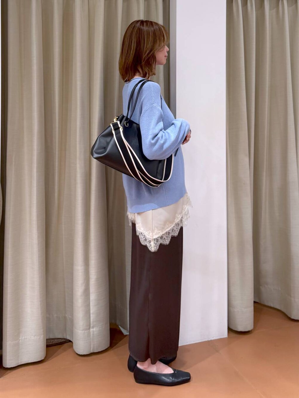 ブルー系のニット/セーター、ブラック系のパンプス、ブラウン系のスカートを着用したレディースの春コーディネートの5枚目の写真