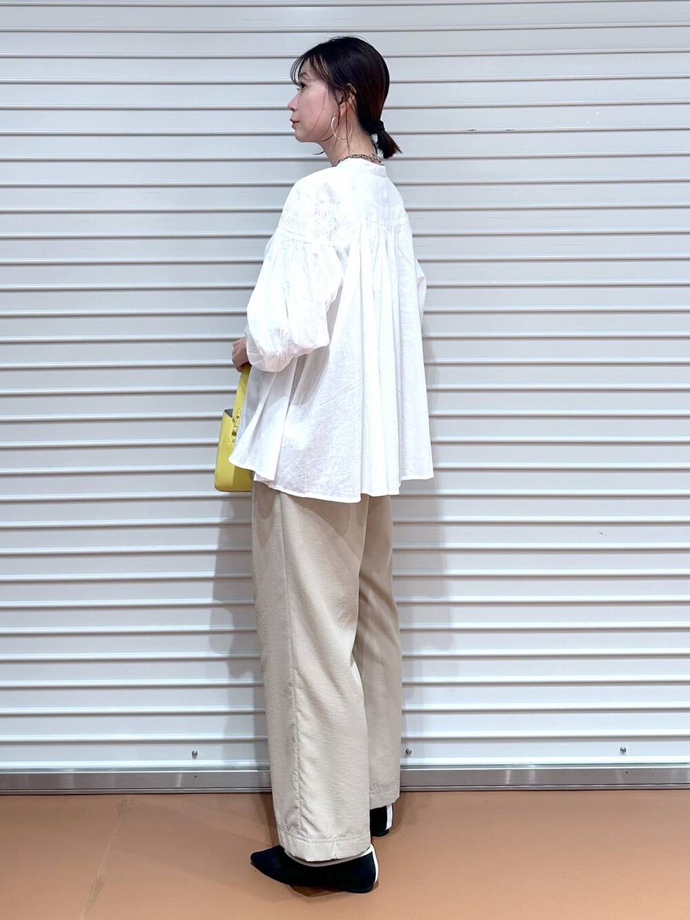 ブラック系のパンプス、ベージュ系のその他パンツ、イエロー系のハンドバッグを着用したレディースの春コーディネートの3枚目の写真