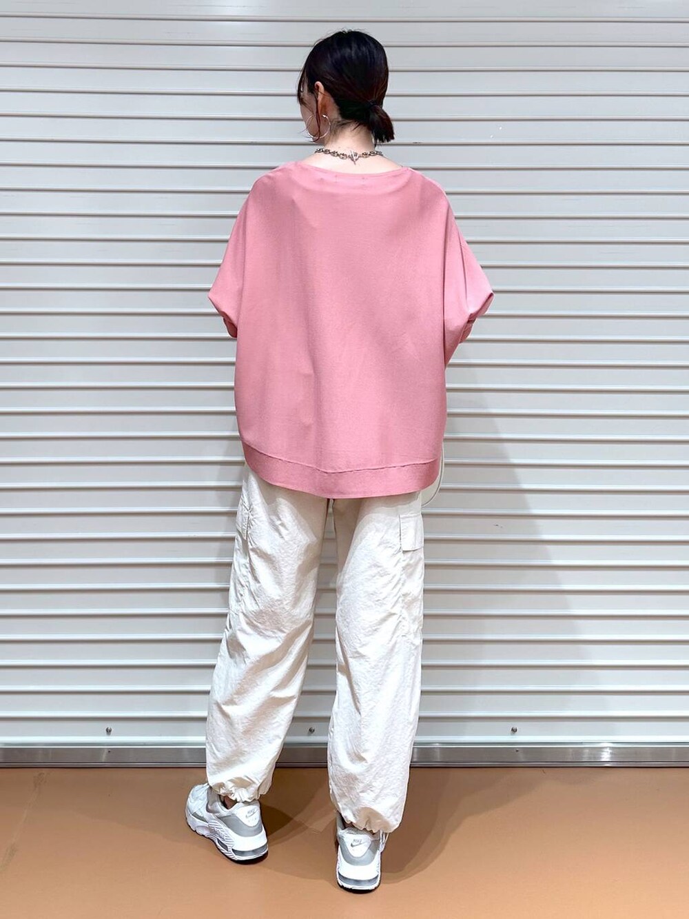 ピンク系のニット/セーター、ホワイト系のハンドバッグ、ホワイト系のカーゴパンツを着用したレディースの春コーディネートの4枚目の写真
