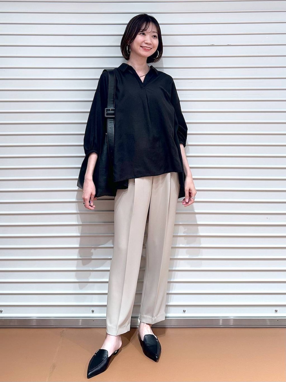 ブラック系のTシャツ/カットソー、ベージュ系のその他パンツ、ブラック系のハンドバッグを着用したレディースの春コーディネートの2枚目の写真