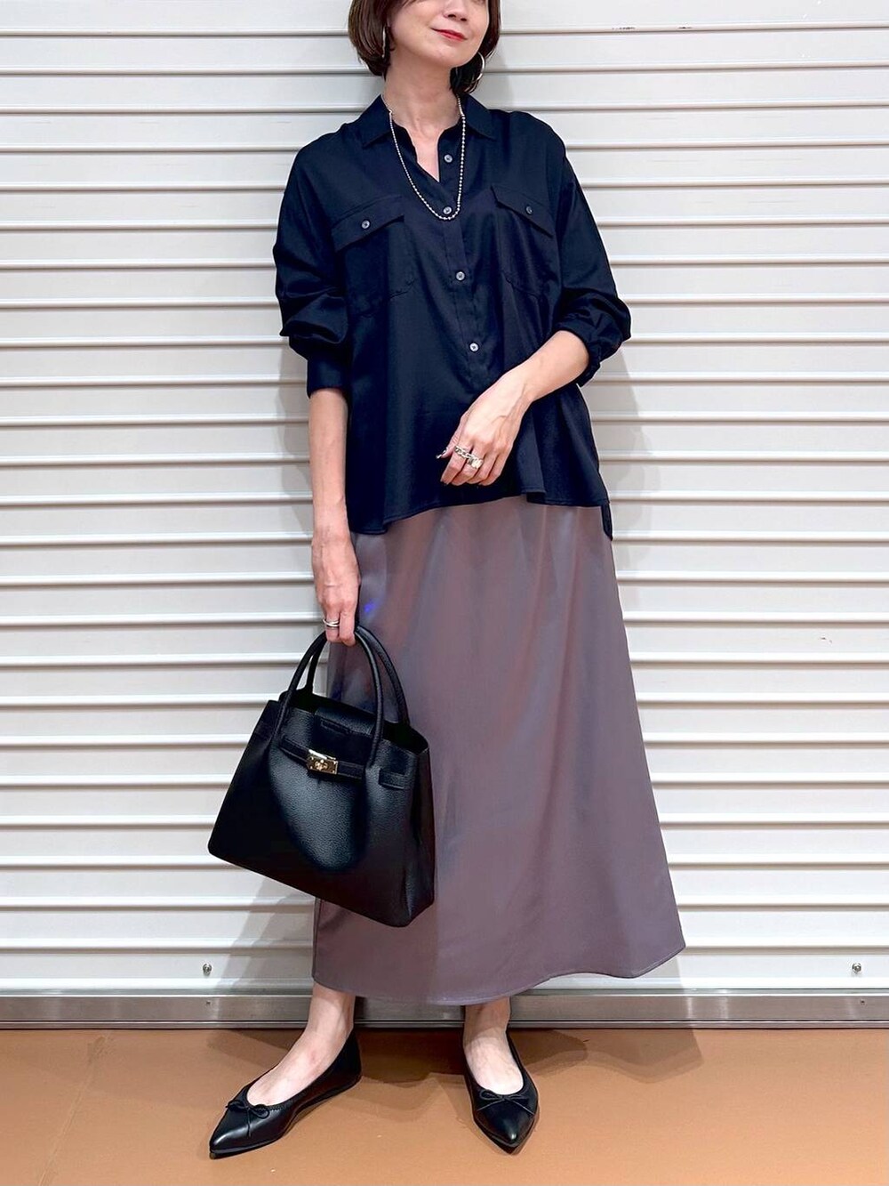ブルー系のシャツ/ブラウス、ブラック系のパンプス、ブラック系のハンドバッグを着用したレディースの秋コーディネートの5枚目の写真