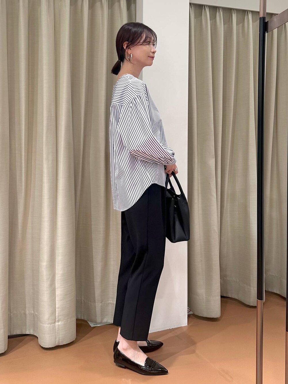 ブラック系のその他パンツ、ブルー系のシャツ/ブラウス、ブラック系のハンドバッグを着用したレディースの春コーディネートの5枚目の写真