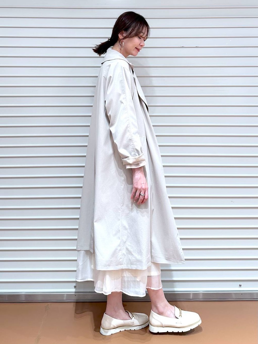 ホワイト系のスカート、ホワイト系のローファー、ホワイト系のハンドバッグを着用したレディースの冬コーディネートの2枚目の写真