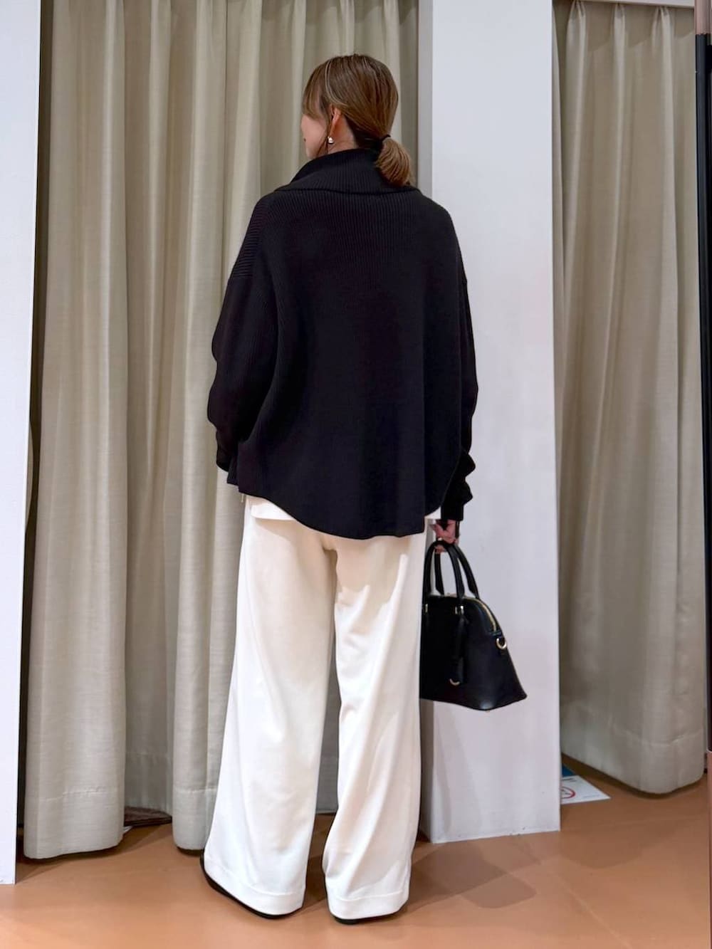 ホワイト系のニット/セーター、ブラック系のカーディガン/ボレロ、ブラック系のハンドバッグを着用したレディースの冬コーディネートの4枚目の写真