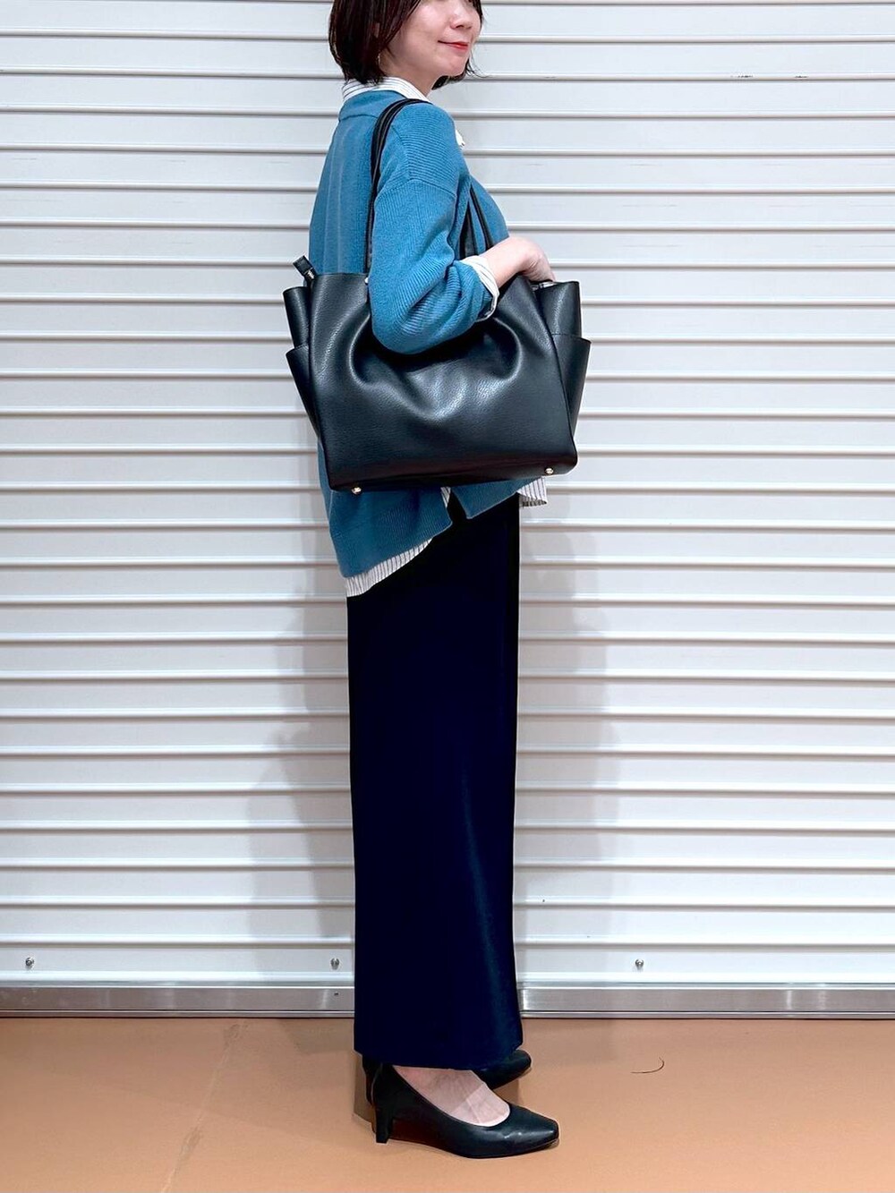 ブラック系のトートバッグ、ブルー系のニット/セーター、ホワイト系のシャツ/ブラウスを着用したレディースの春コーディネートの3枚目の写真