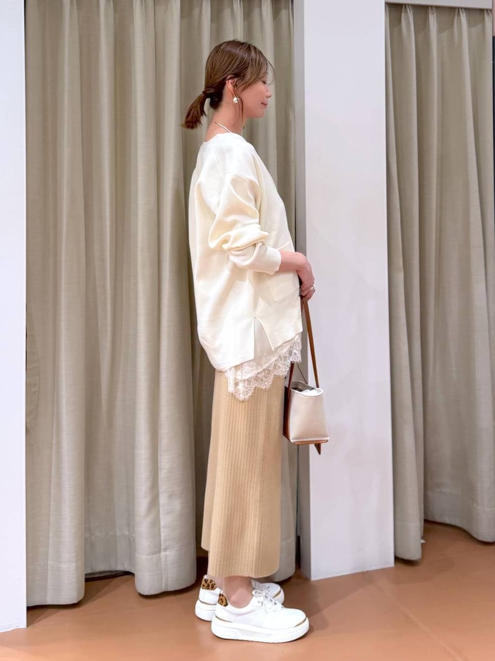 ホワイト系のカーディガン/ボレロ、ベージュ系のスカート、ホワイト系のキャミソールを着用したレディースの冬コーディネートの4枚目の写真
