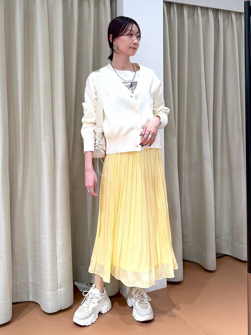 イエロー系のスカート、ホワイト系のカーディガン/ボレロ、ホワイト系のTシャツ/カットソーを着用したレディースの冬コーディネートの2枚目の写真