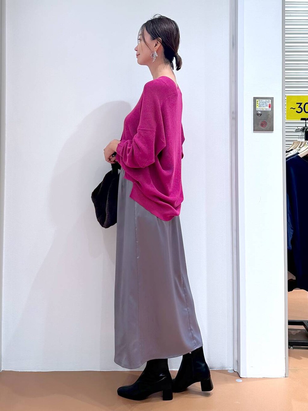 ピンク系のニット/セーター、グレー系のスカート、ブラック系のブーツを着用したレディースの秋コーディネートの3枚目の写真