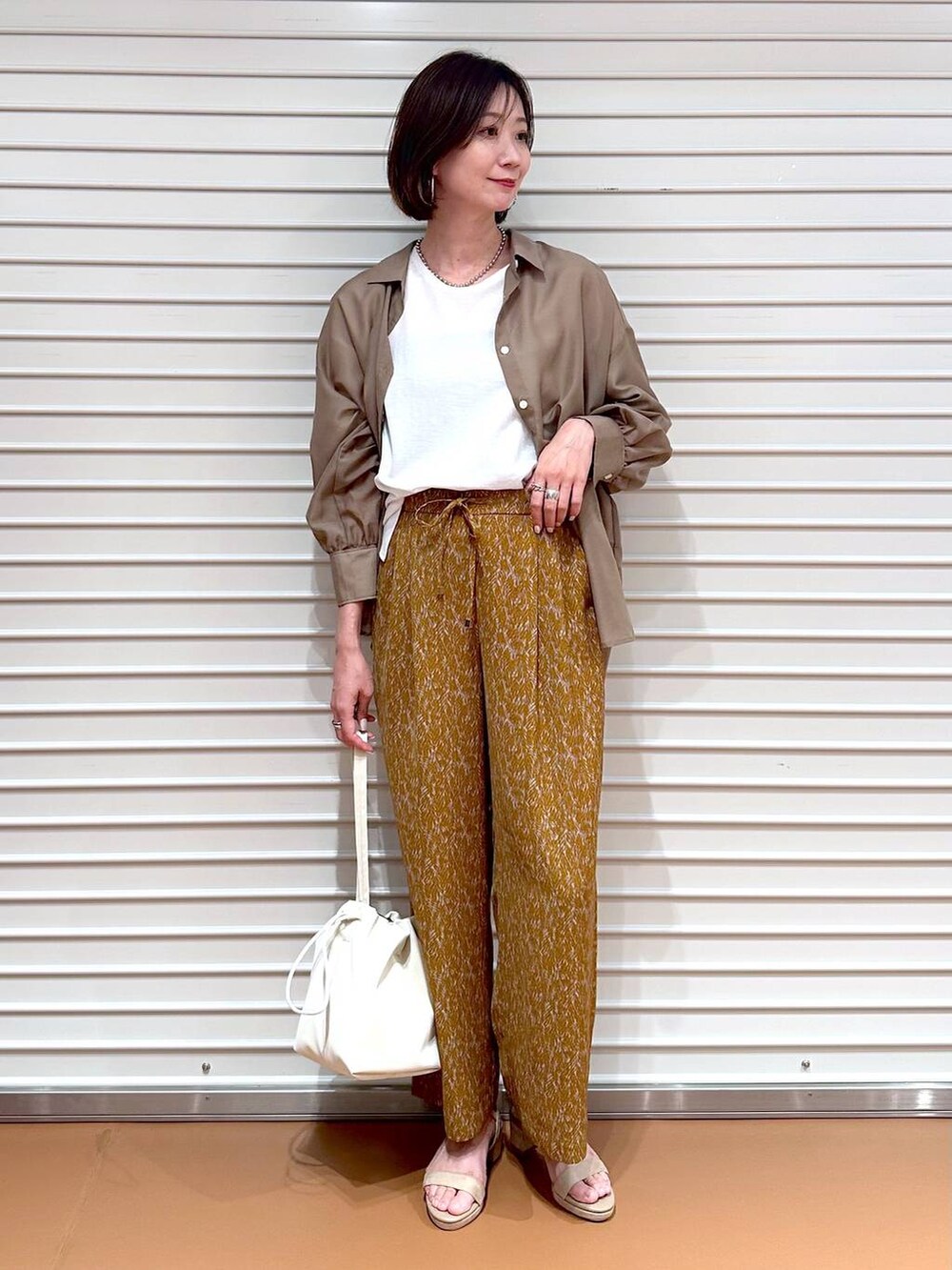 ベージュ系のサンダル、ブラウン系のその他パンツ、ホワイト系のTシャツ/カットソーを着用したレディースの秋コーディネートの2枚目の写真