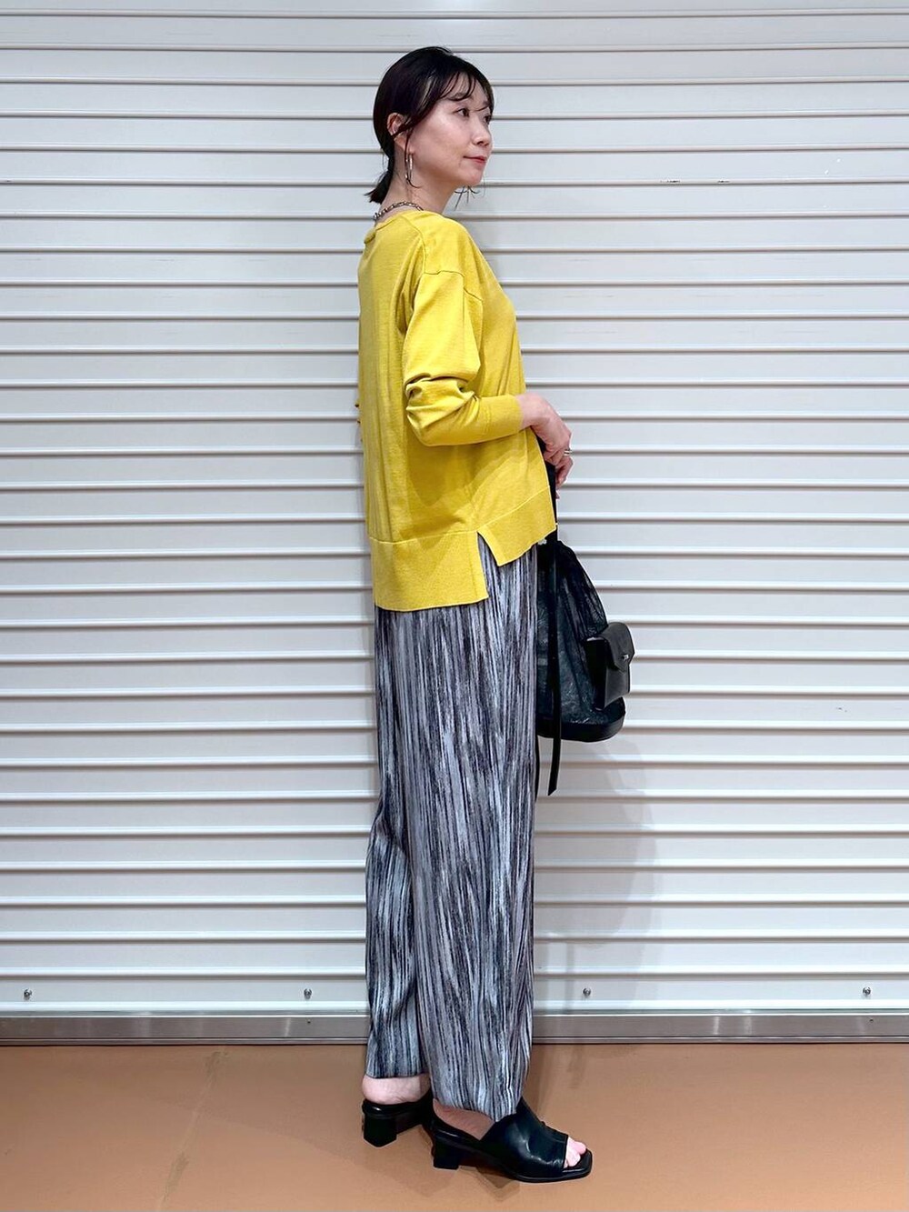 ブラック系のサンダル、グレー系のその他パンツ、イエロー系のニット/セーターを着用したレディースの春コーディネートの3枚目の写真