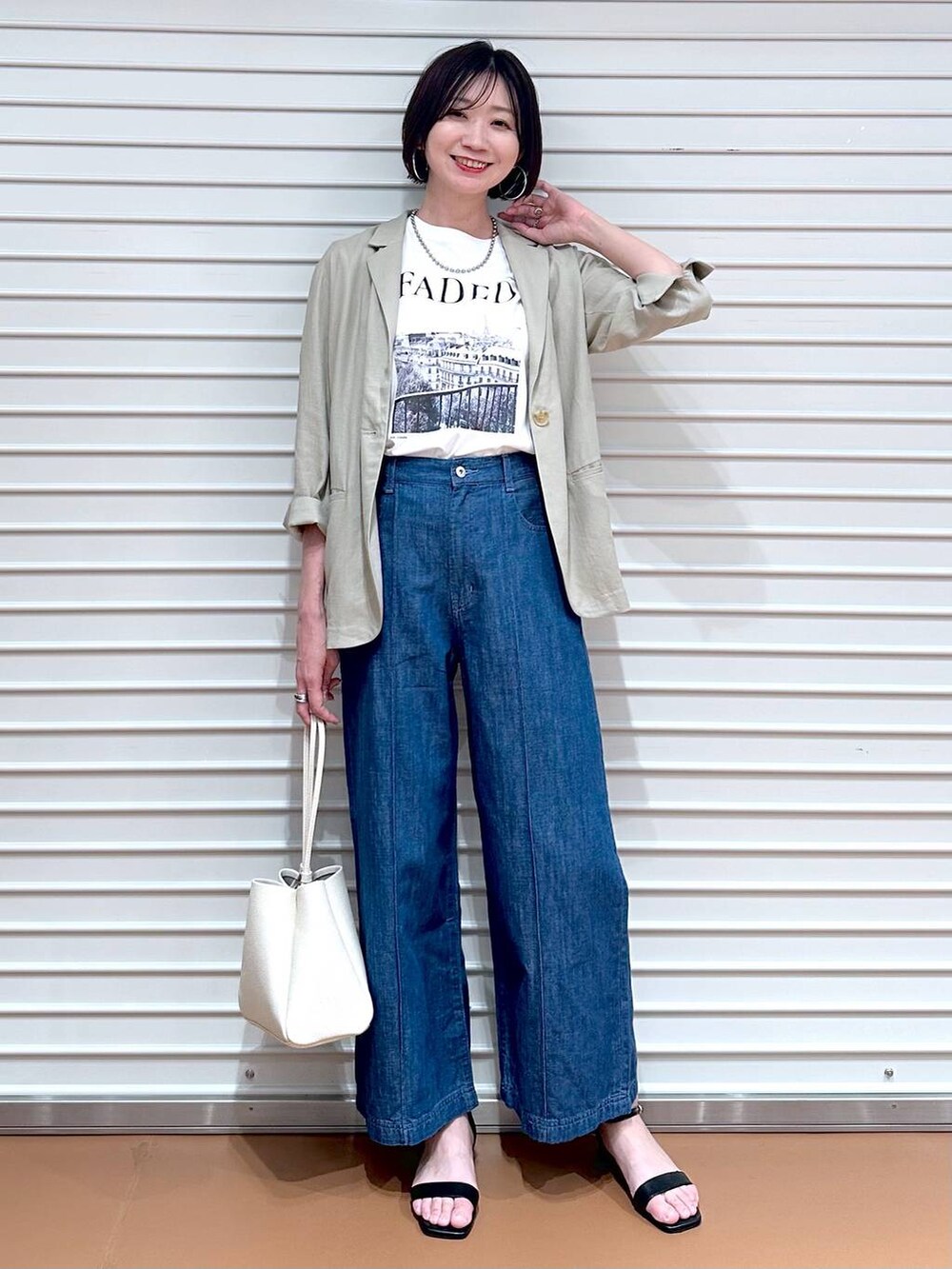 ブルー系のデニムパンツ、ブルー系のデニムパンツ、ブラック系のサンダルを着用したレディースの夏コーディネートの2枚目の写真