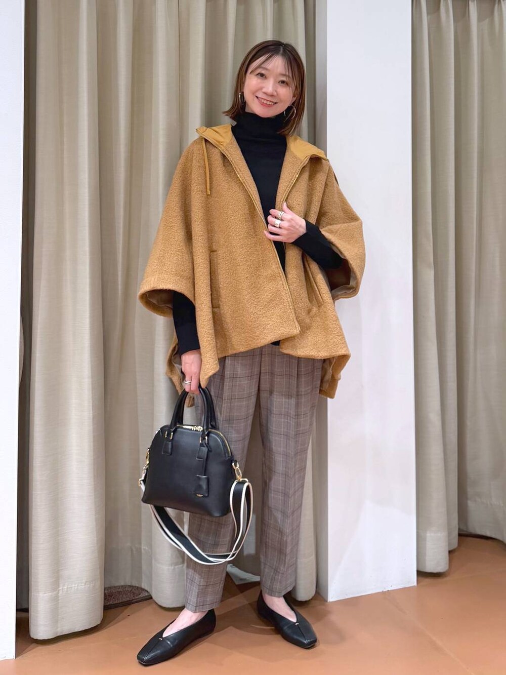 ブラック系のハンドバッグ、ブラック系のスラックス、ブラック系のパンプスを着用したレディースの冬コーディネートの6枚目の写真