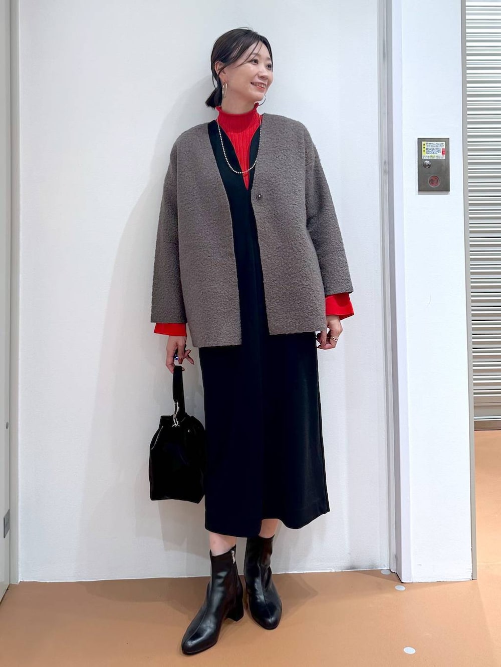 ブラック系のジャンパースカート、ブラック系のブーツ、ブラウン系のノーカラージャケットを着用したレディースの秋コーディネートの2枚目の写真