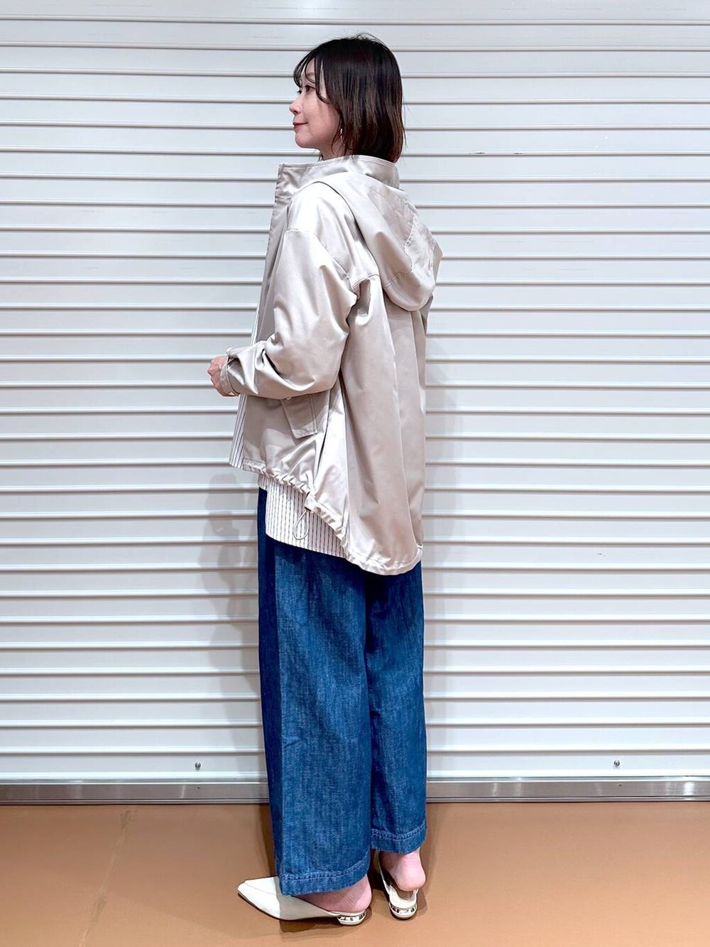 ブルー系のデニムパンツ、ホワイト系のシャツ/ブラウス、ベージュ系のマウンテンパーカーを着用したレディースの春コーディネートの2枚目の写真