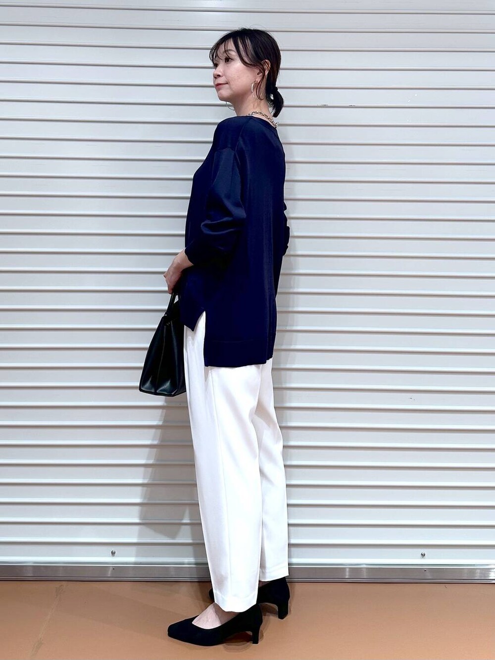 ブルー系のニット/セーター、ブラック系のショルダーバッグ、ホワイト系のその他パンツを着用したレディースの春コーディネートの3枚目の写真