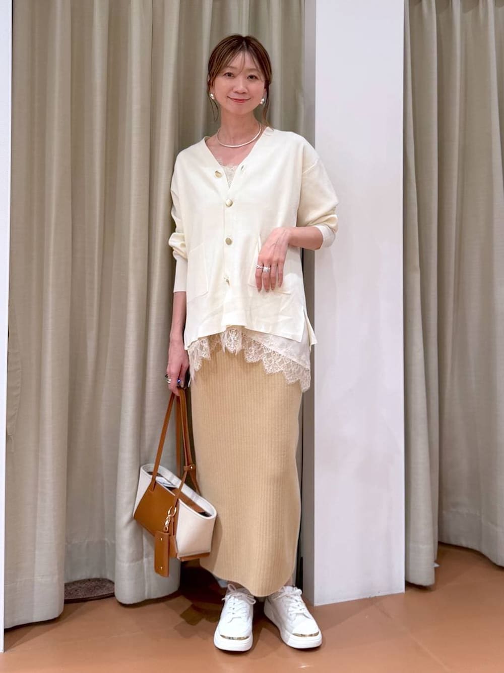 ホワイト系のカーディガン/ボレロ、ベージュ系のスカート、ホワイト系のキャミソールを着用したレディースの冬コーディネートの3枚目の写真