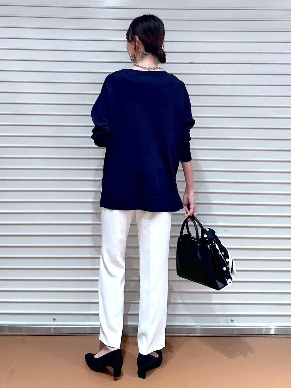ブルー系のニット/セーター、ブラック系のショルダーバッグ、ホワイト系のその他パンツを着用したレディースの春コーディネートの4枚目の写真