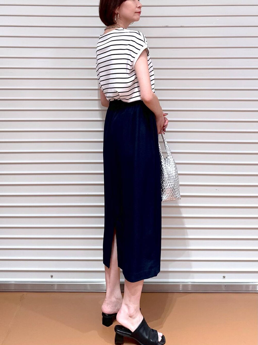 シルバー系のトートバッグ、ブラック系のサンダル、ブルー系のTシャツ/カットソーを着用したレディースの夏コーディネートの6枚目の写真