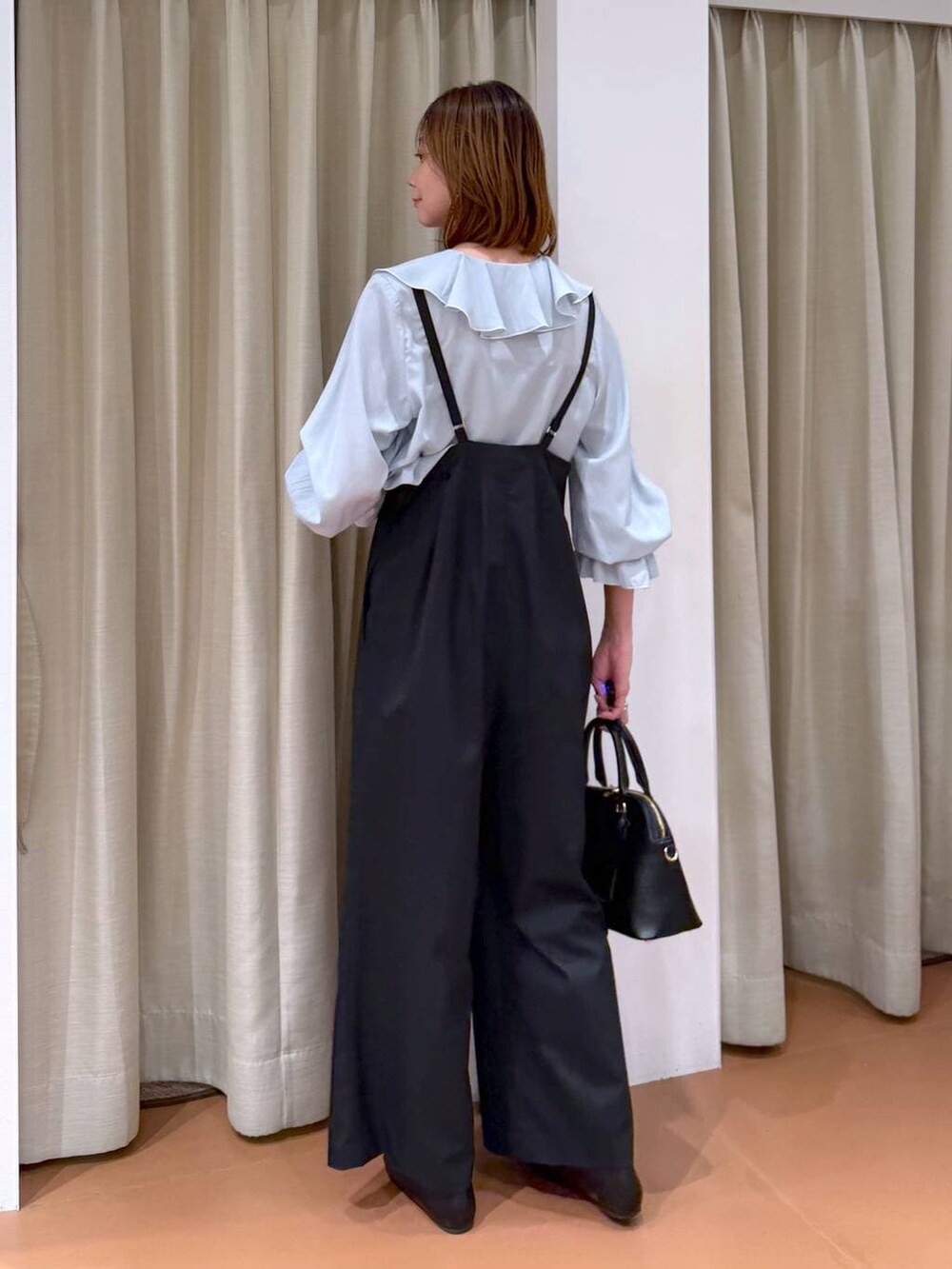 ブラック系のハンドバッグ、ブラック系のパンプス、ブルー系のシャツ/ブラウスを着用したレディースの冬コーディネートの4枚目の写真